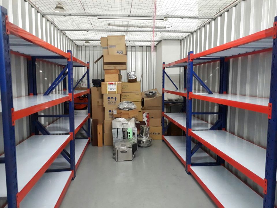 Warehouse racks lining both walls of a storage facility with cartons in the middle